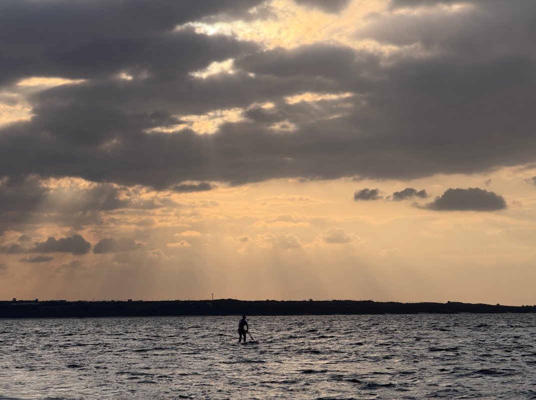 夕暮れの沖縄の海を漕ぎ進む来間翔太