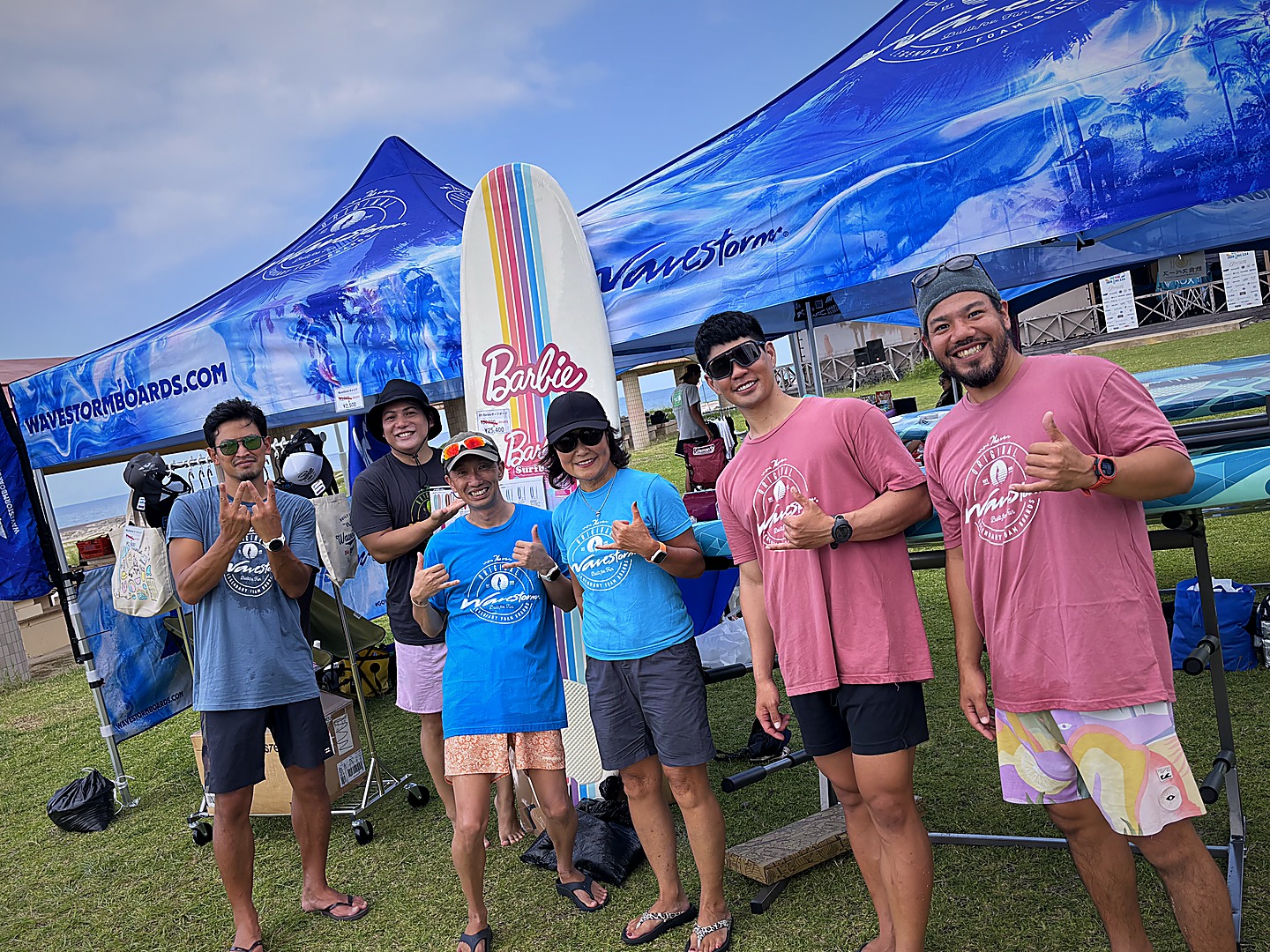 Wavestorm展示ブースとサーフボード・SUPボードの前に立つ来間翔太とチーム